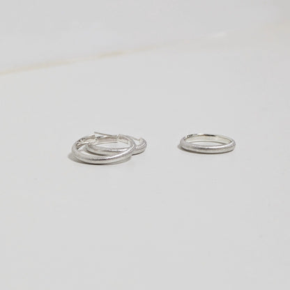 Two satin textured hoops and matching silver ring on white background