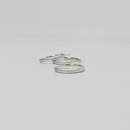 Two satin textured hoops and matching silver ring on white background