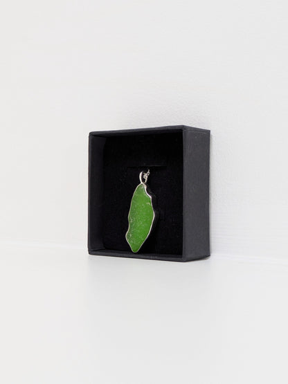 Side view of a large green sea glass pendant in a black display box with a white background.