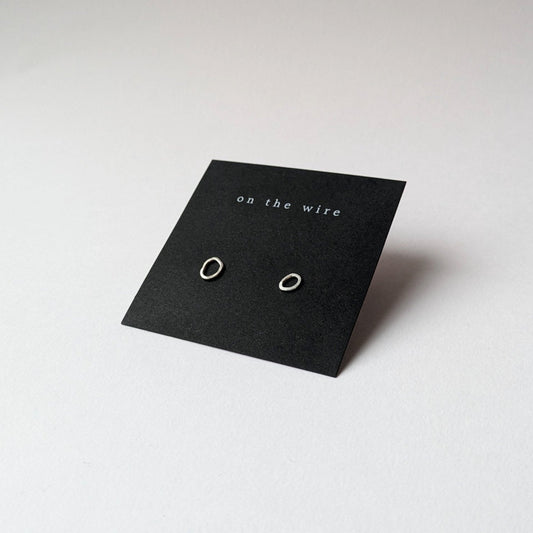 Silver pebble stud earrings in branded gift card on white background