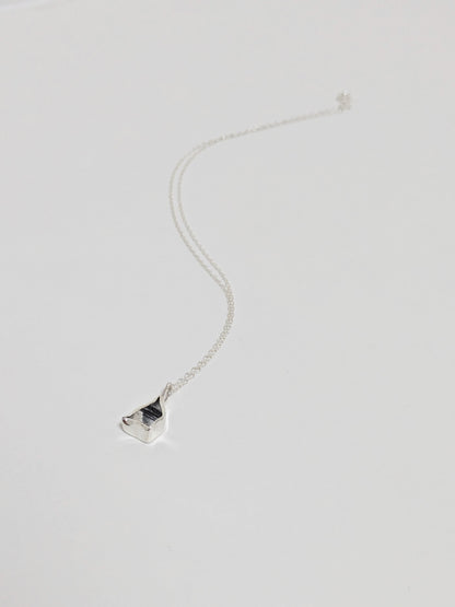 Mini black and white sea pottery pendant with a thin silver chain on a white background.