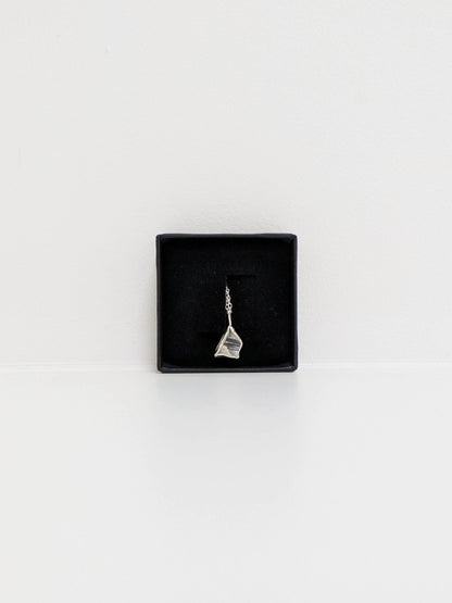 Mini black and white sea pottery pendant with a thin silver chain in a black display box on a white background.