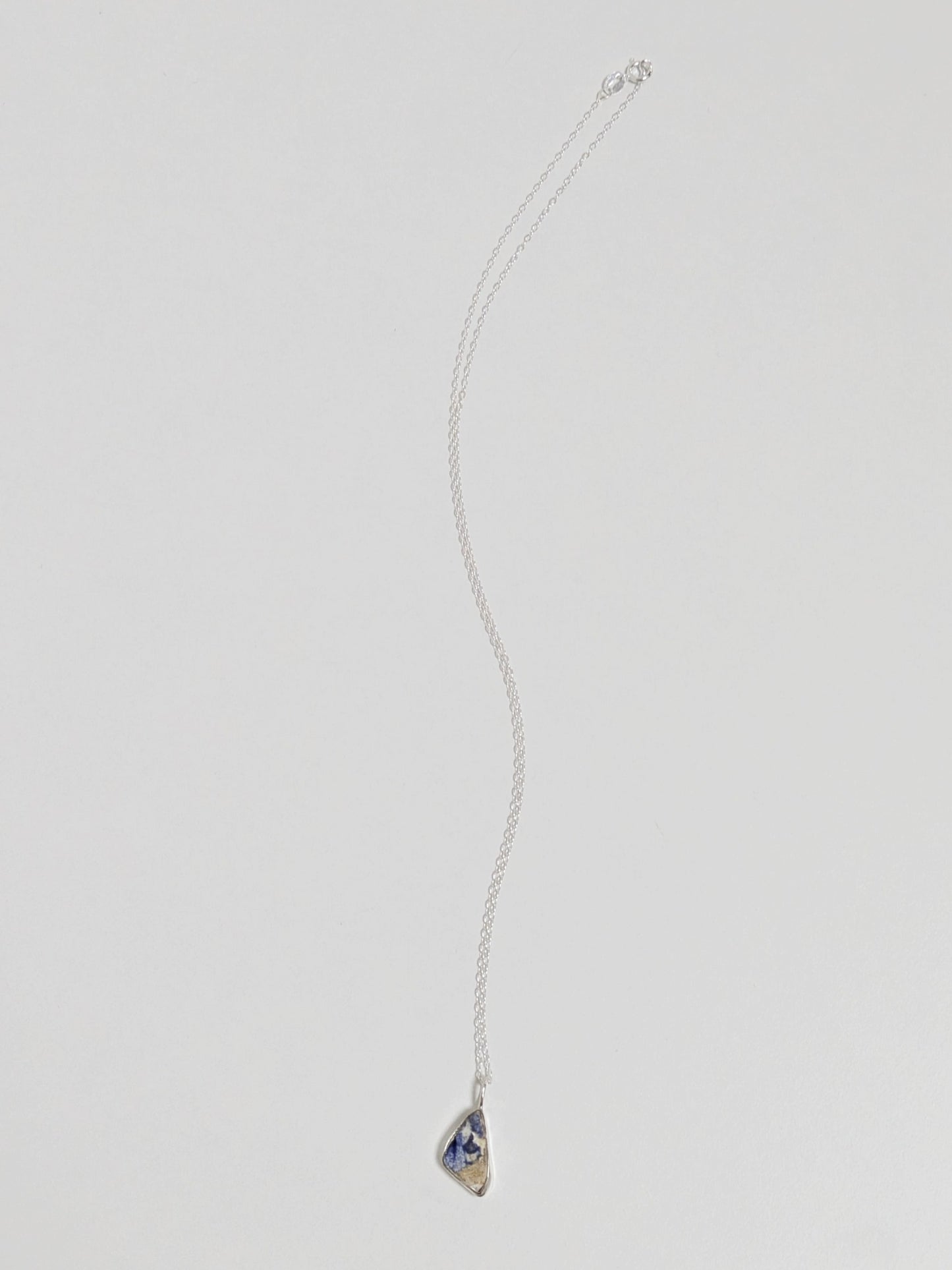 Mini blue and white sea pottery necklace on white background.