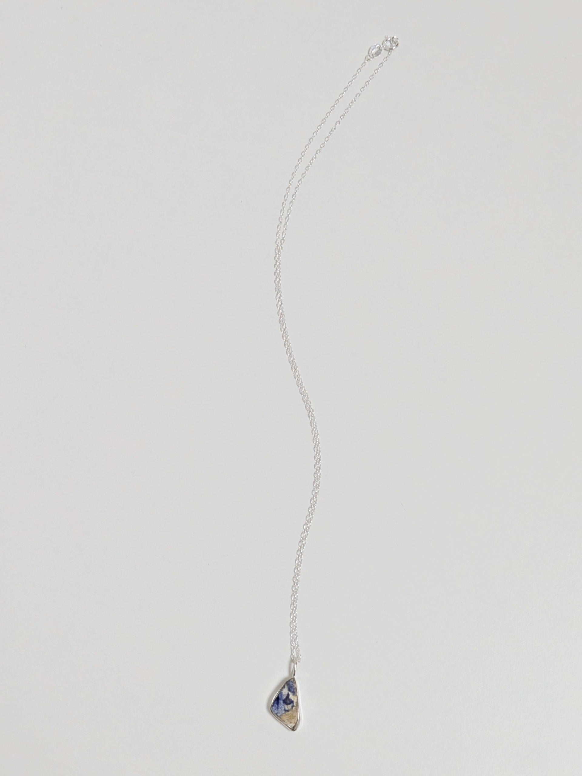 Mini blue and white sea pottery necklace on white background.