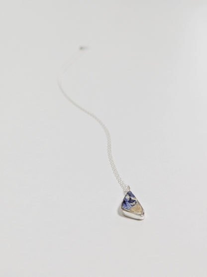 Close up of mini blue and white sea pottery necklace on white background.