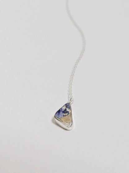 Close up of mini blue and white sea pottery necklace on white background.