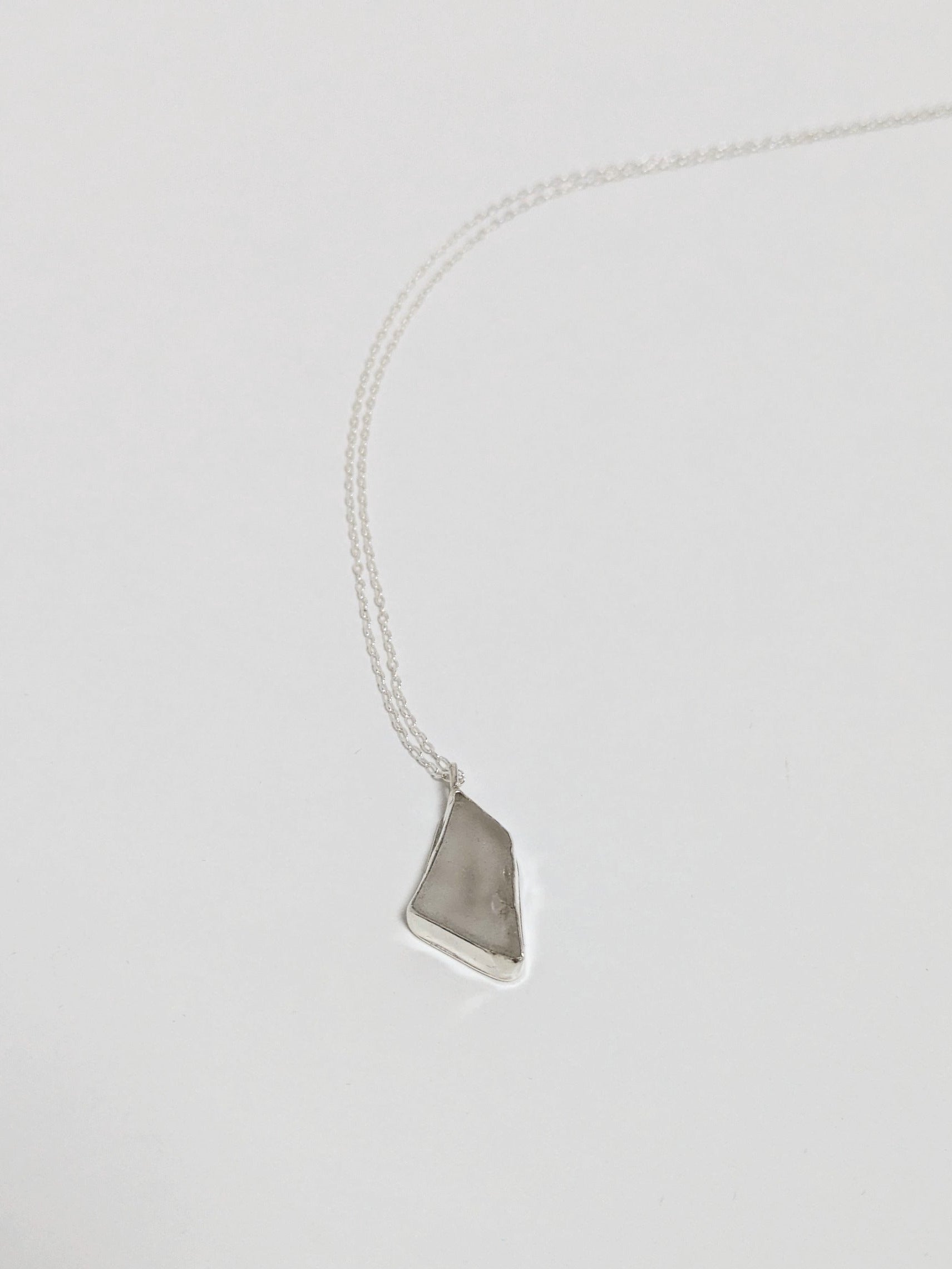 Necklace with a white sea glass pendant on a light gray background