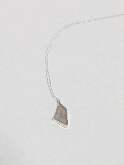 Necklace with a white sea glass pendant on a light gray background
