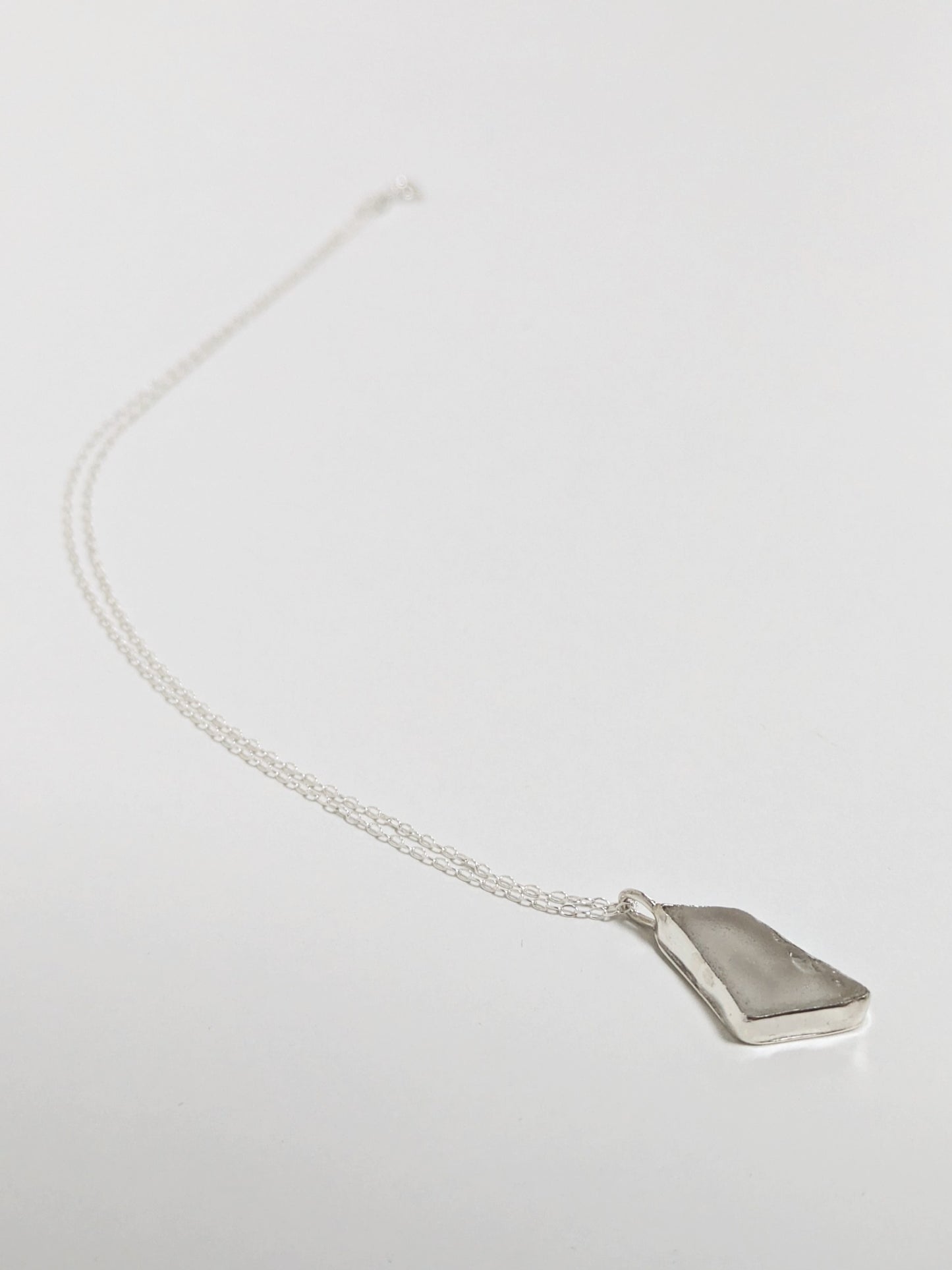 White sea glass necklace on a light gray background