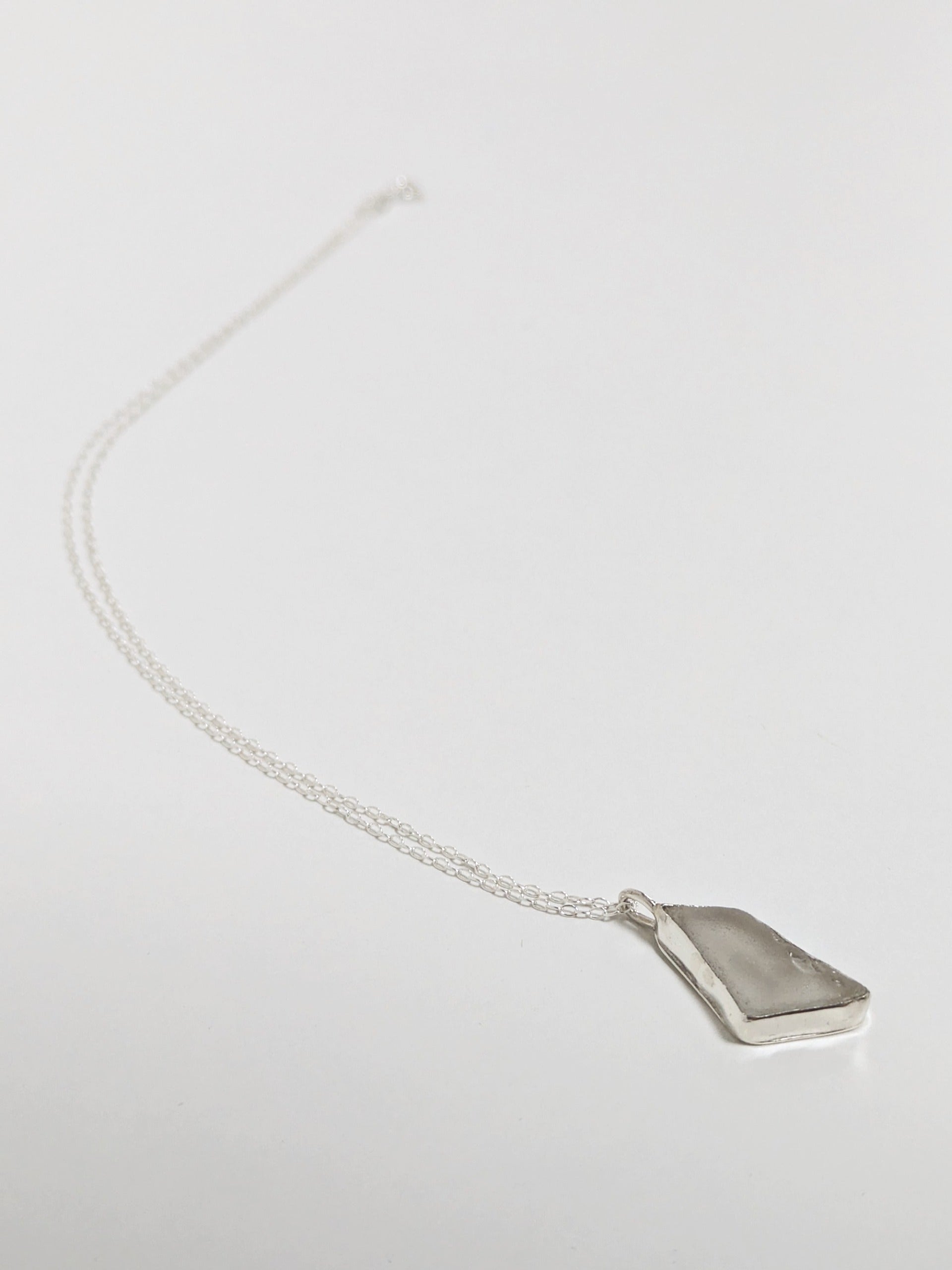 White sea glass necklace on a light gray background