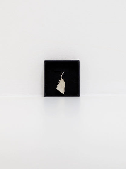 White sea glass pendant in a black jewellery box on a white background