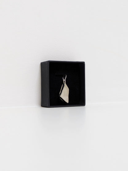 White sea glass pendant on a silver chain in a black jewellery box on a white background