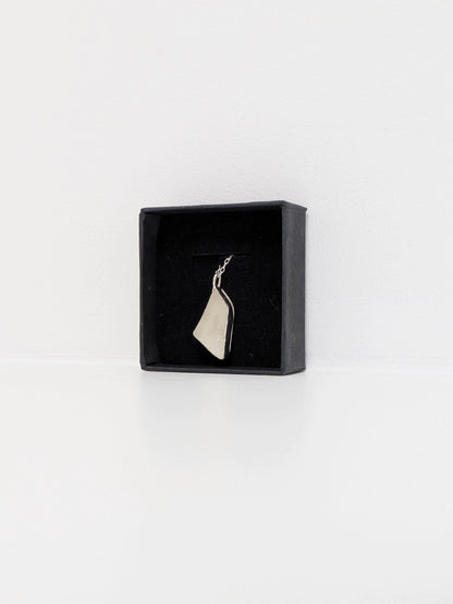 White sea glass pendant in a black jewellery box on a white background